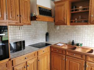 a kitchen with wooden cabinets and a sink at Maisonnette au calme in Sully-sur-Loire