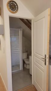 a bathroom with a toilet and a clock on the wall at Les sapins 201 in Charquemont
