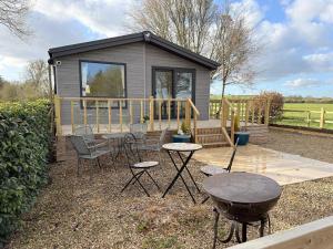 a tiny house with a table and chairs and a grill at Fleece Lodge in Bledington
