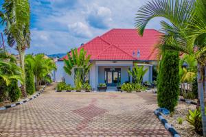 a house with a red roof and palm trees at Ritha Motel Apartment in Kigali