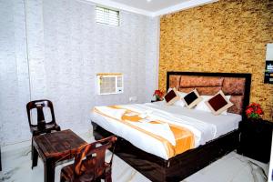a bedroom with a large bed and a chair at Hotel Ayodhya in Ayodhya