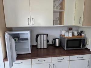 a kitchen with white cabinets and a microwave and a refrigerator at Privatunterkunft Bingum in Leerort