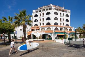 two men with surfboards walking in front of a building at Ocean Mark Holiday Parque Santiago 2 in Playa de las Americas