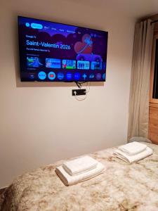 a flat screen tv hanging on a wall above a bed at L Ecrin des Cimes 6 voyageurs in Arâches-la-Frasse