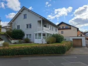 a white house with a garage in front of it at Ferienwohnung Am Anger in Unterleinach
