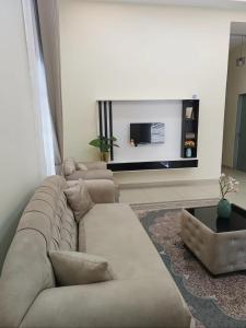 a living room with two couches and a flat screen tv at Dirindu homestay in Temerloh