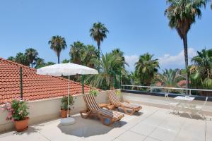 two chairs and an umbrella on a balcony with palm trees at Arkk Homes in Antalya