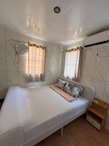 a white bed in a small room with two windows at Amalia Homes Staycation in Palo