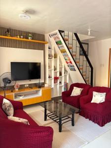 a living room with two red chairs and a tv at Amalia Homes Staycation in Palo