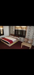 a bedroom with a bed and a chair and a window at Hotel Sangla Retreat in Sāngla