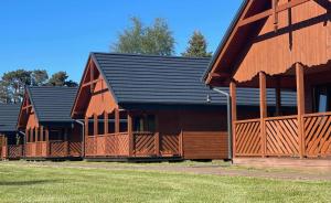 two large wooden barns with a black roof at Domki Alex in Dębki