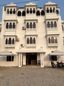 a large white building with two motorcycles parked in front of it at Lotus hotel in Nāthdwāra