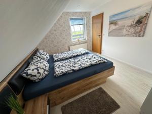 a bed with pillows on it in a room at Rosenhaus Esens - Wohnung Backbord in Esens