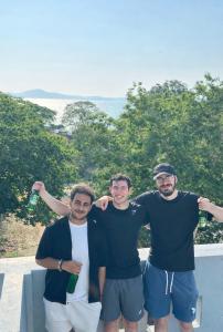 a group of three men posing for a picture at Hostel Friends Station & Cafe in Pattaya South
