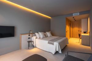 a hotel room with a bed and a flat screen tv at The Alma Suite in Alora