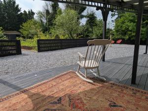 a white rocking chair sitting on a wooden deck at Woodville Barn in Ród