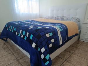 a bed with a blue and white blanket on it at Large and cozy studio in Piera