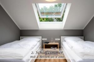 two beds in a room with a window at Ferienwohnung Frieda - Gulfhof nahe Greetsiel mit Sauna, Garten & 3 Schlafzimmern in Krummhörn
