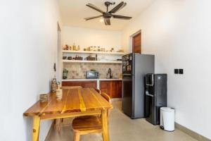 a kitchen with a wooden table and a refrigerator at Roh Villas Kuta Lombok in Kuta Lombok