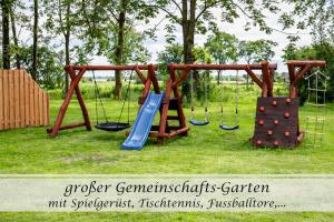 a playground with two swings and a slide at Ferienwohnung Frieda - Gulfhof nahe Greetsiel mit Sauna, Garten & 3 Schlafzimmern in Krummhörn