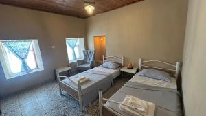 a room with two beds and a chair and two windows at Pergamon Yunt Evleri in Bergama