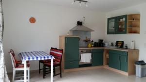 a kitchen with green cabinets and a table and a stove at Ferienwohnung ANKER in Lubmin +4 photos