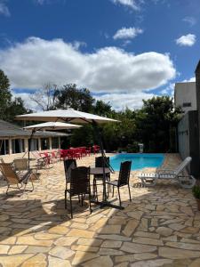 a table with chairs and an umbrella next to a pool at Pousada Avenida in Tibagi