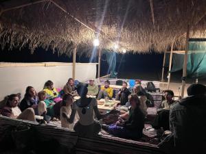 a group of people sitting around a table in a hut at Eden Camp Abu Galum in Dahab