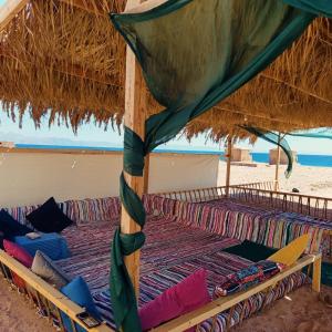 a group of beds under a straw umbrella on the beach at Eden Camp Abu Galum in Dahab