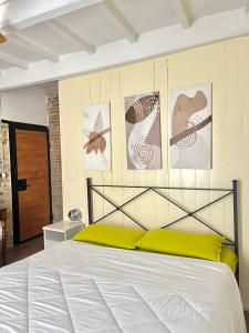 a bedroom with a white bed with paintings on the wall at La Casa di Alice in Perugia