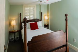 a bedroom with a wooden bed with a red pillow at The Historic General Stanton Inn in Charlestown