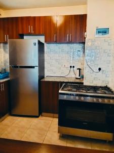 a kitchen with a stove and a stainless steel refrigerator at Peaceful Paradise in Gatunga