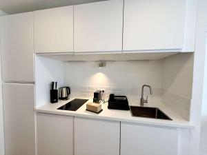 a white kitchen with a sink and a refrigerator at B044 Studio moderne Croisette 100m in Cannes +4 photos