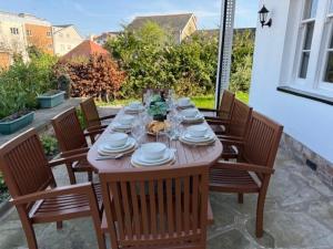 a wooden table with chairs and plates on a patio at Luxury 6 bed house by the sea in Rhos-on-Sea
