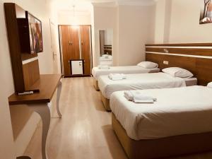 a hotel room with three beds and a desk at Larok Hotel in Akcaabat