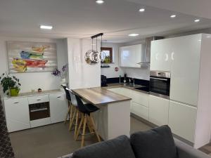 a kitchen with white cabinets and a bar with stools at Apartment Goran in Senj