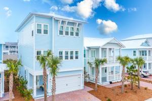 a blue house with palm trees in front of it at Happily Eva After at Prominence 30A in Inlet Beach