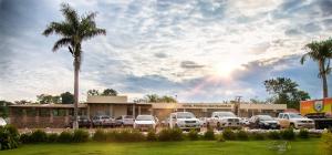a parking lot with cars parked in front of a building at Hotel Pousada das Palmeiras in Colíder