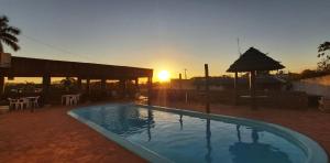 a swimming pool with the sunset in the background at Hotel Pousada das Palmeiras in Colíder