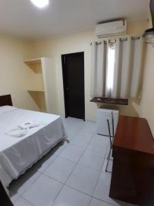 a bedroom with a bed and a desk and a window at Hotel Pousada das Palmeiras in Colíder