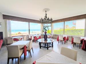 ein Esszimmer mit Tischen und Stühlen und großen Fenstern in der Unterkunft Hotel Uhainak in Hendaye