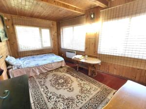 a bedroom with a bed and a table and windows at Калина in Deneshi