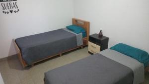 a bedroom with two beds and a dresser with a night stand at Bracco in Chos Malal