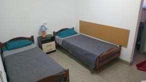 a bedroom with two beds and a night stand with a lamp at Bracco in Chos Malal