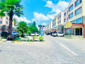 a cobblestone street in a city with buildings and palm trees at D&H Homes Milimani Nakuru-Elegant 2 Bedroom Apartment in Nakuru