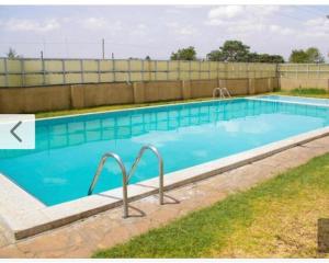 a large swimming pool with blue water at D&H Homes Milimani Nakuru-Elegant 2 Bedroom Apartment in Nakuru
