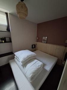 a bed with white sheets and pillows in a room at Appartement Véronica - Villa Damary in La Bourboule