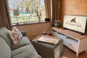 a living room with a couch and two glasses of wine at Tiny Haus Seeadler in Schwasdorf