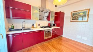 a kitchen with red cabinets and a sink at 威尼斯Mestre火车站明亮舒适便捷整套公寓Casa Marco in Marghera