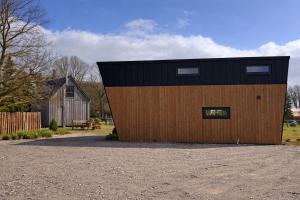 a large wooden building with a black roof at Tiny Haus Seeadler in Schwasdorf
